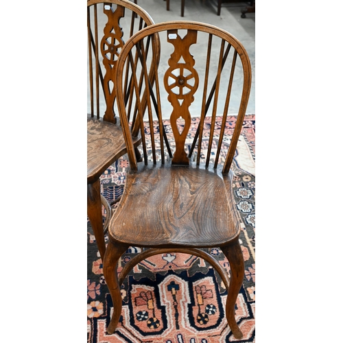 51 - A set of four provincial elm seated wheel back dining chairs with turned legs and crinoline front st... 