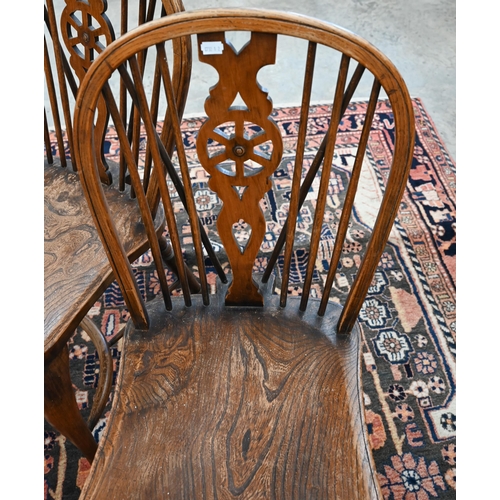 51 - A set of four provincial elm seated wheel back dining chairs with turned legs and crinoline front st... 