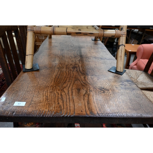 87 - A small elm refectory dining table on shaped trestle supports united by pegged mortice and tenon str... 