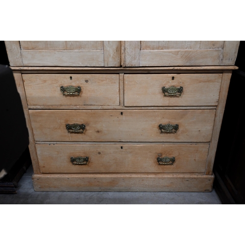 91 - An antique pine linen press with panelled doors enclosing shelved interior on chest base with two sh... 