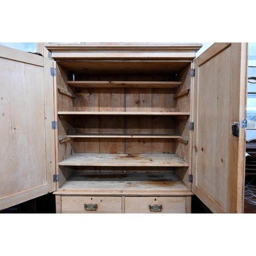 91 - An antique pine linen press with panelled doors enclosing shelved interior on chest base with two sh... 