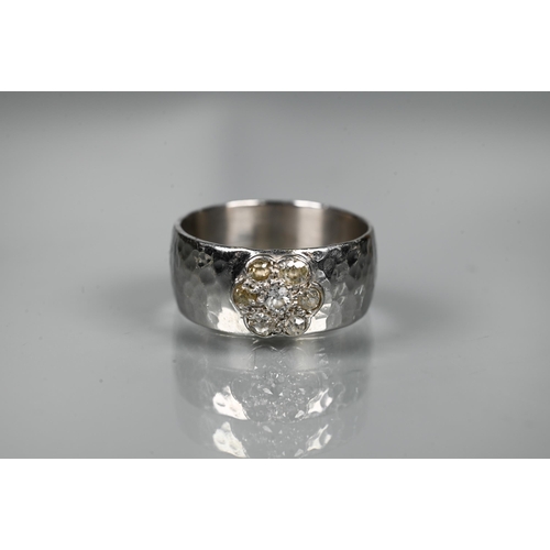 231 - A contemporary 9ct white gold wide band with hammered finish, set with seven-stone diamond cluster, ... 