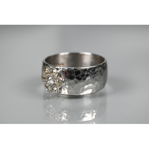 231 - A contemporary 9ct white gold wide band with hammered finish, set with seven-stone diamond cluster, ... 