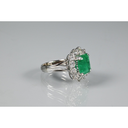 270 - A rectangular cluster ring, the central natural emerald surrounded by twelve brilliant cut diamonds,... 