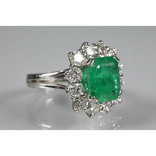 270 - A rectangular cluster ring, the central natural emerald surrounded by twelve brilliant cut diamonds,... 