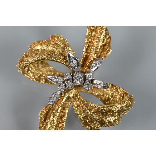 281 - An 18ct yellow gold brooch of textured form, set with mixed cut diamonds, in the form of a bow, appr... 