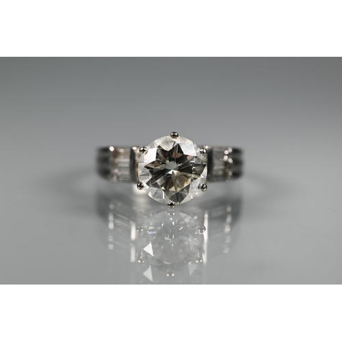 A diamond ring, the central round brilliant cut stone with four round brilliant cut diamonds to each side, and a further three baguette cut diamonds to shoulders, white metal set stamped PT, size P 1/2, approx 7.3g all in, c/w EGL certificate US UH105981104