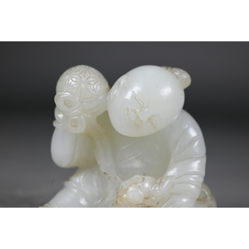 384 - An 18th century Chinese jade carving of a boy and karashisi playing with a ribbon tied brocade ball,... 