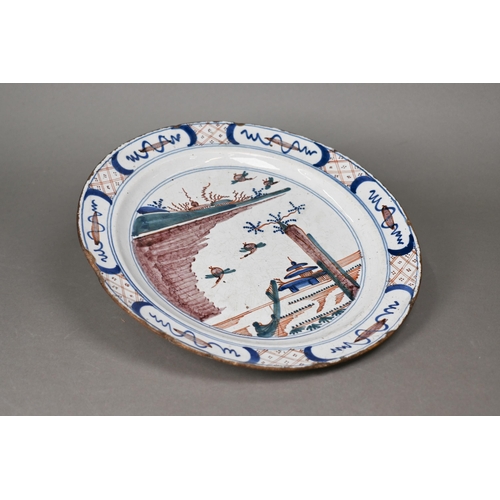 505 - An 18th century polychrome Delft charger, painted with traditional coastal landscape with ducks land... 