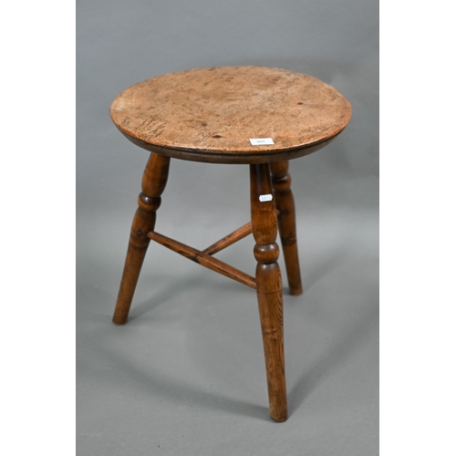 807 - An antique walnut and elm cricket table, the circular top raised on three turned legs united by a t-...