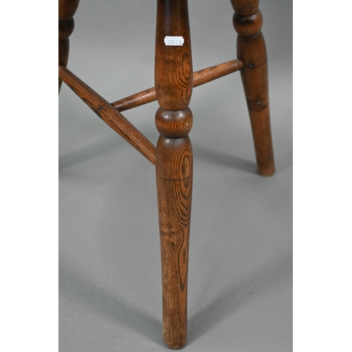 807 - An antique walnut and elm cricket table, the circular top raised on three turned legs united by a t-... 