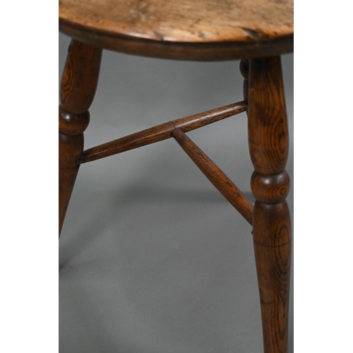 807 - An antique walnut and elm cricket table, the circular top raised on three turned legs united by a t-... 