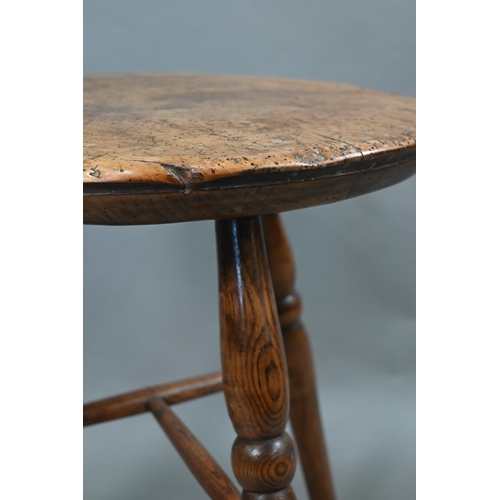 807 - An antique walnut and elm cricket table, the circular top raised on three turned legs united by a t-... 