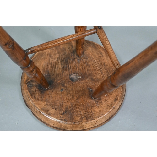 807 - An antique walnut and elm cricket table, the circular top raised on three turned legs united by a t-... 