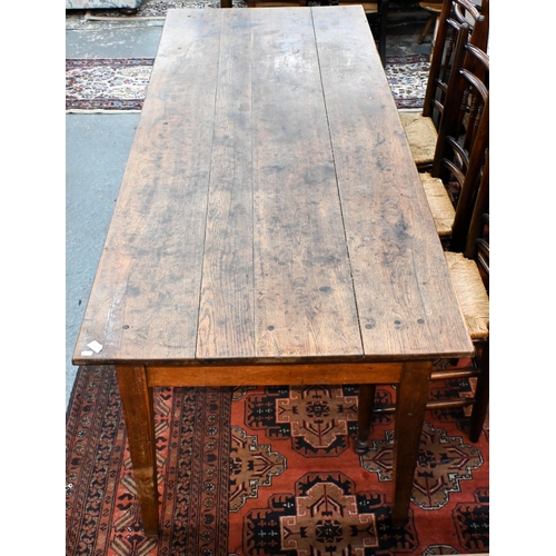 827 - An antique French oak refectory dining table, the plank top over two frieze drawers to one side, rai...