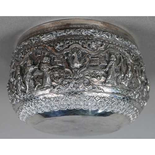 35 - A Burmese low grade silver bowl, embossed and chased with deities and animals in woodland settings, ... 