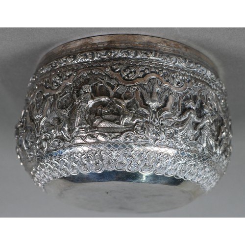 35 - A Burmese low grade silver bowl, embossed and chased with deities and animals in woodland settings, ... 