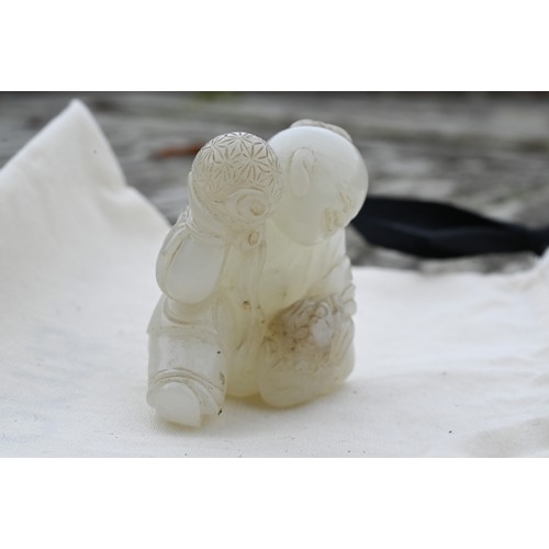 384 - An 18th century Chinese jade carving of a boy and karashisi playing with a ribbon tied brocade ball,... 