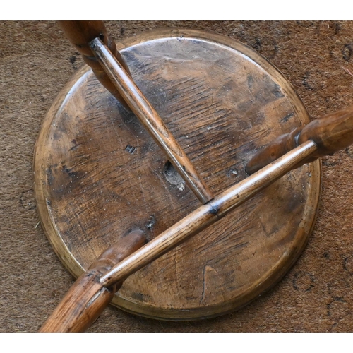 807 - An antique walnut and elm cricket table, the circular top raised on three turned legs united by a t-... 