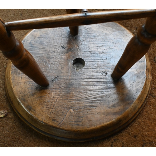 807 - An antique walnut and elm cricket table, the circular top raised on three turned legs united by a t-... 