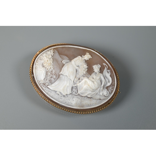 164 - An oval shell cameo brooch featuring young maidens with bouquets of flowers, signed to reverse, in 9... 