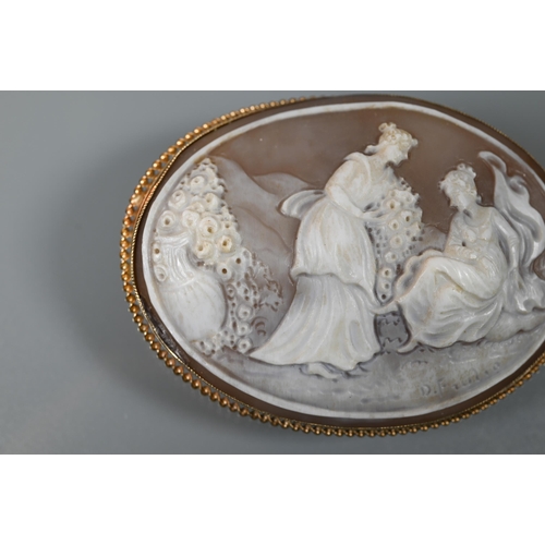 164 - An oval shell cameo brooch featuring young maidens with bouquets of flowers, signed to reverse, in 9... 