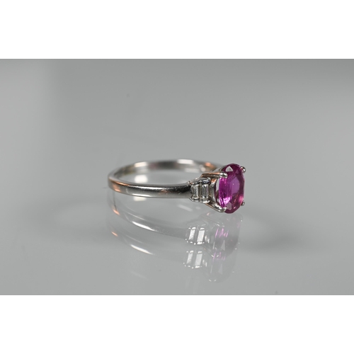 190 - A pink sapphire and diamond ring, the central oval claw set pink sapphire flanked by two graduated b... 