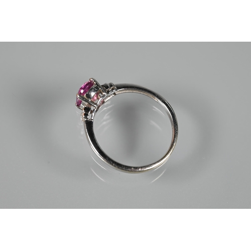 190 - A pink sapphire and diamond ring, the central oval claw set pink sapphire flanked by two graduated b... 