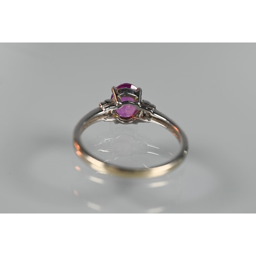 190 - A pink sapphire and diamond ring, the central oval claw set pink sapphire flanked by two graduated b... 