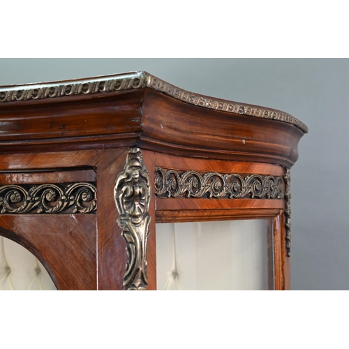 833 - A continental brass mounted kingwood serpentine form salon display cabinet, the interior with button... 