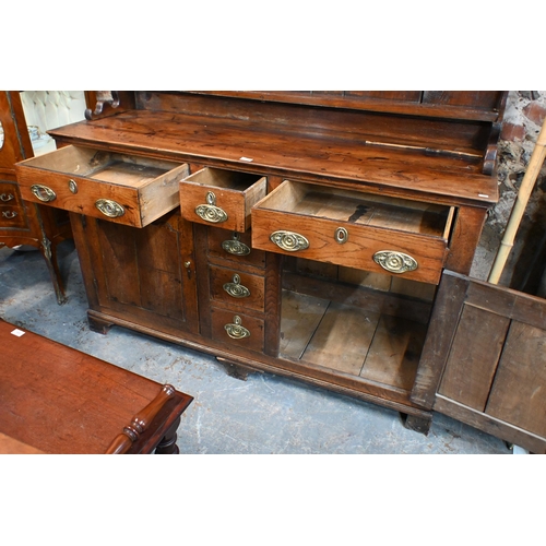 883 - An 18th century fruitwood and oak/elm dresser, the wavy cornice top with plank back over three shelv... 