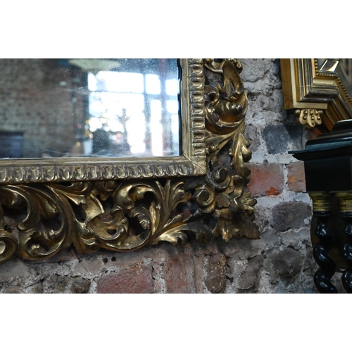 909 - An antique carved foliate scroll formed giltwood framed mirror, 97 cm x 110 cm