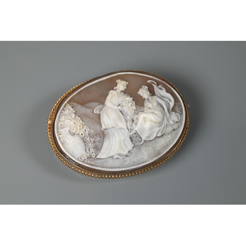 516 - An oval shell cameo brooch featuring young maidens with bouquets of flowers, signed to reverse, in 9... 