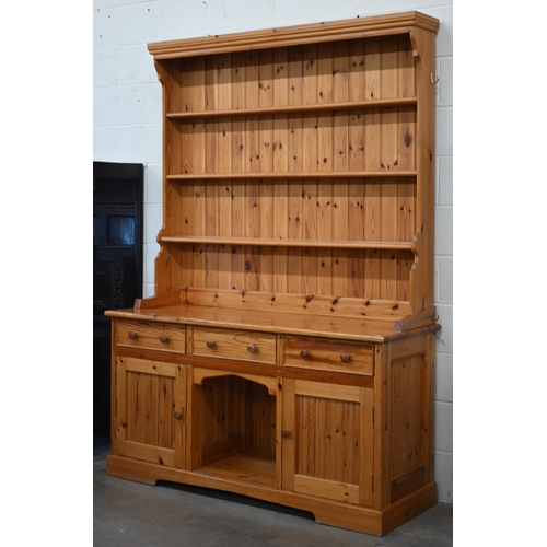 135 - A stained pine dresser with tall three shelf plate rack on a base with three drawers and panelled cu... 