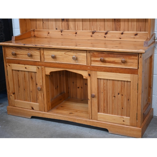 135 - A stained pine dresser with tall three shelf plate rack on a base with three drawers and panelled cu... 