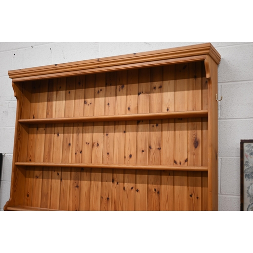 135 - A stained pine dresser with tall three shelf plate rack on a base with three drawers and panelled cu... 