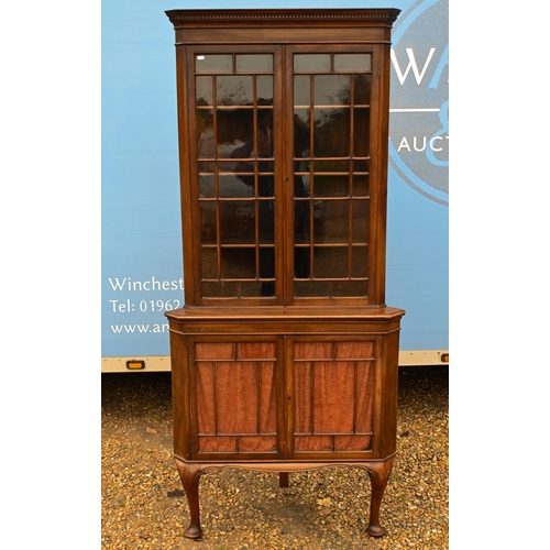 39 - # An Edwardian floor standing corner cabinet with glazed doors enclosing shelves, raised on pad-foot... 