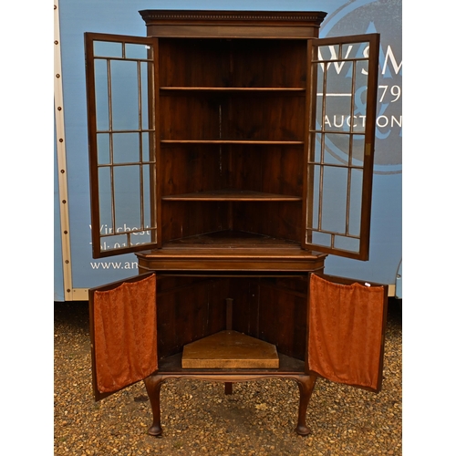 39 - # An Edwardian floor standing corner cabinet with glazed doors enclosing shelves, raised on pad-foot... 