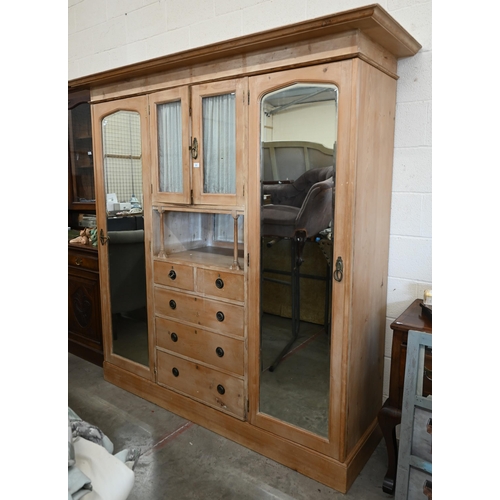 102 - A Continental pine compactum wardrobe, the central section with glazed doors over the open niche and... 