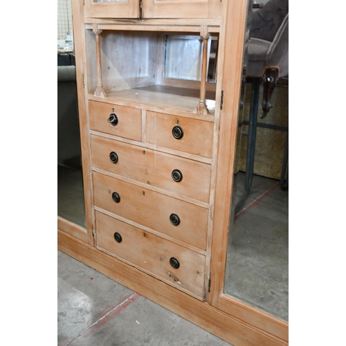 102 - A Continental pine compactum wardrobe, the central section with glazed doors over the open niche and... 