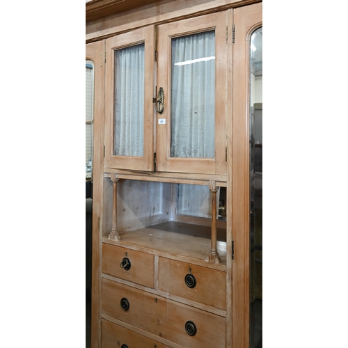 102 - A Continental pine compactum wardrobe, the central section with glazed doors over the open niche and... 