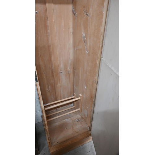 102 - A Continental pine compactum wardrobe, the central section with glazed doors over the open niche and... 