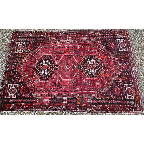 106 - A South West Persian Shiraz rug with central triple medalion on red ground surrounded by a stylised ... 