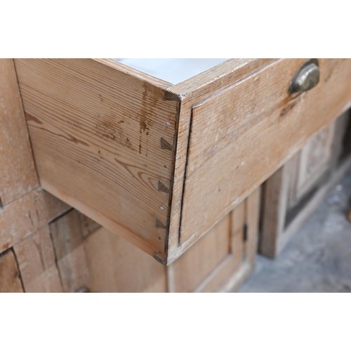 136 - An antique pine kitchen dresser base with two drawers over panelled cupboard doors (top with routed ... 