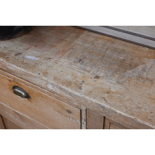 136 - An antique pine kitchen dresser base with two drawers over panelled cupboard doors (top with routed ... 