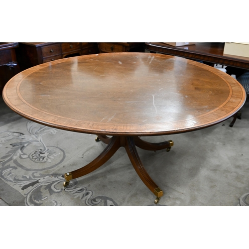 144 - A circular tilt-top mahogany crossbanded dining table on turned column and splayed legs with brass c... 