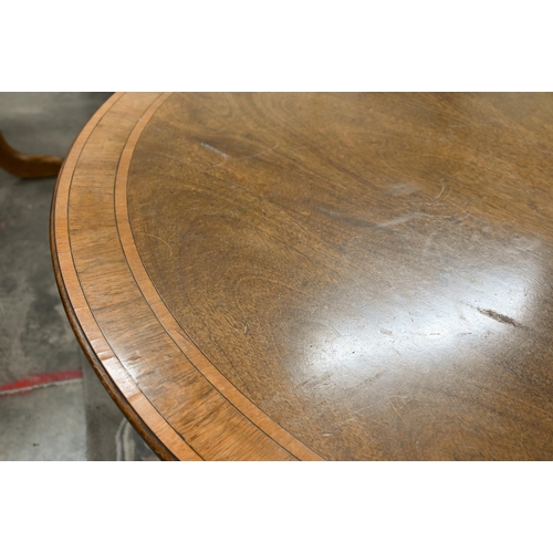 144 - A circular tilt-top mahogany crossbanded dining table on turned column and splayed legs with brass c... 