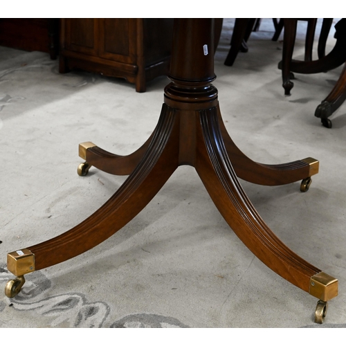 144 - A circular tilt-top mahogany crossbanded dining table on turned column and splayed legs with brass c... 