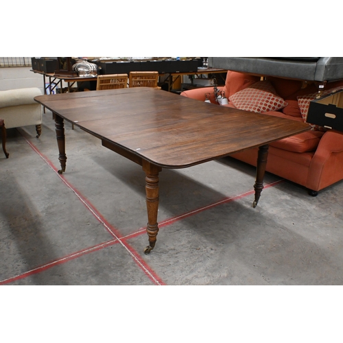 147 - A 19th century mahogany extending dining table with drop-leaf ends and two central leaves raised on ... 