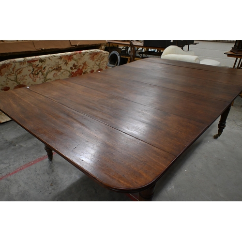 147 - A 19th century mahogany extending dining table with drop-leaf ends and two central leaves raised on ... 